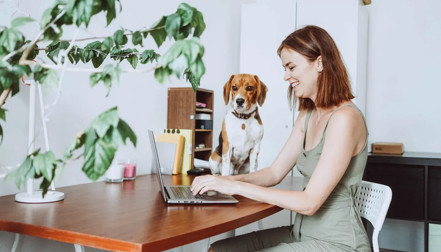 Woman faxing from home laptop with her dog 