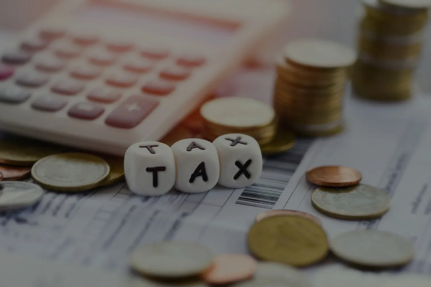 Calculator, coins and cubes that spell "tax"